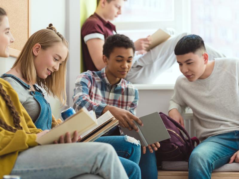 Billedet viser fem teenagere der læser bøger sammen