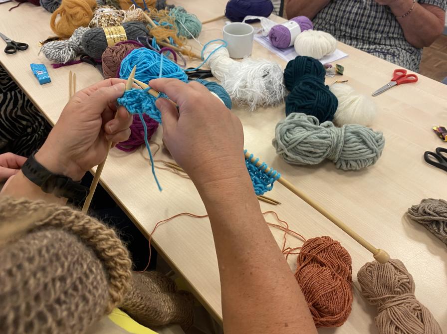 Billedet viser et par hænder, der er i gang med at strikke