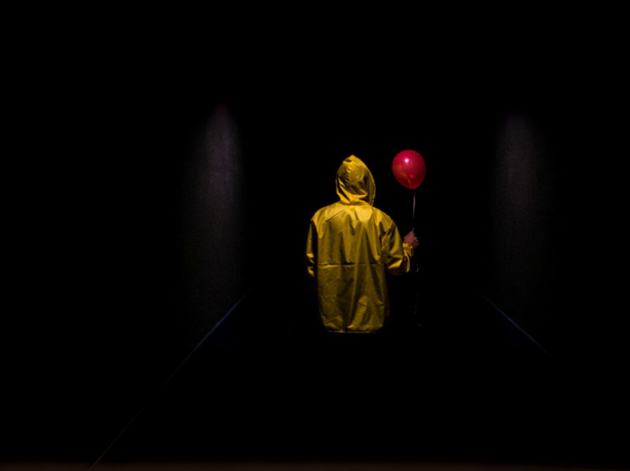 Person med gul regnjakke og rød ballon set bagfra